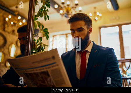 Homme élégant reading newspaper in a cafe Banque D'Images