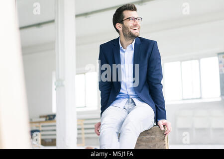 Happy businessman sitting on caisse dans vide bureau loft Banque D'Images