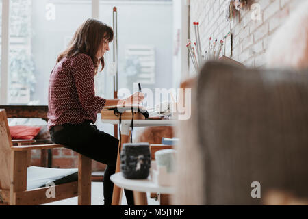 Femme assise en studio la prise de notes Banque D'Images