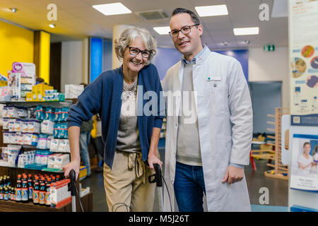 Portrait of smiling pharmacien et client avec roues walker en pharmacie Banque D'Images