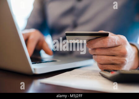 Man using laptop and holding credit card, close-up Banque D'Images