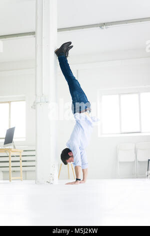 Businessman doing a handstand in office Banque D'Images