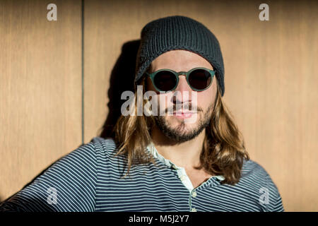 Portrait d'homme barbu aux cheveux longs portant des lunettes de soleil et chapeau laineux Banque D'Images