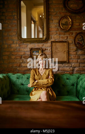 Portrait of smiling elegant woman sitting on a couch Banque D'Images