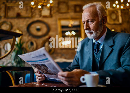 Elegant man reading newspaper in a cafe Banque D'Images