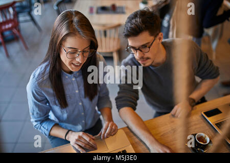 Jeune femme et l'homme dans un café avec un ordinateur portable Banque D'Images