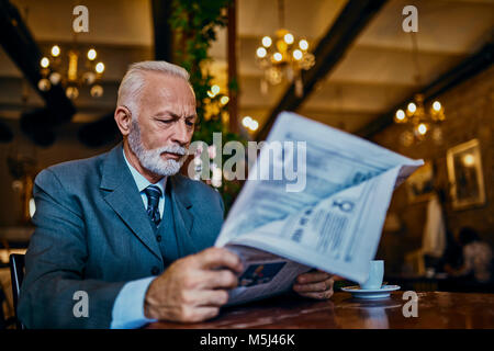 Elegant man reading newspaper in a cafe Banque D'Images