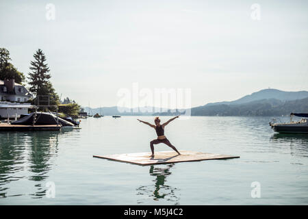 Woman practicing yoga on raft dans un lac Banque D'Images