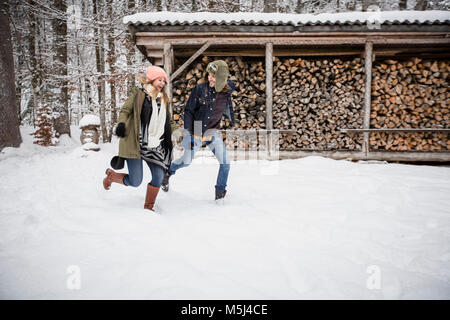 Couple heureux tournant en face de pile de bois à l'extérieur en hiver Banque D'Images