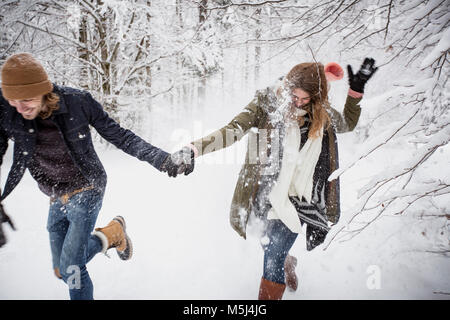 Heureux couple fonctionnant en forêt d'hiver Banque D'Images