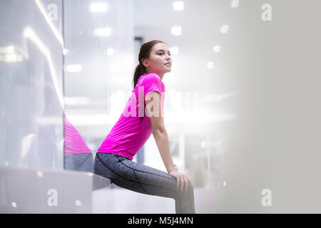 Jeune femme en rose sportshirt se reposant après une course Banque D'Images