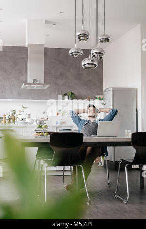 Jeune homme détente à table dans la cuisine Banque D'Images