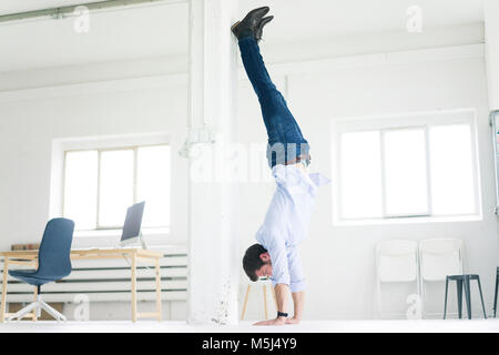 Businessman doing a handstand in office Banque D'Images