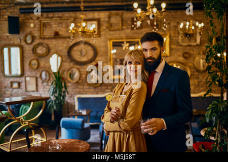 Portrait de couple élégant avec des boissons dans un bar Banque D'Images