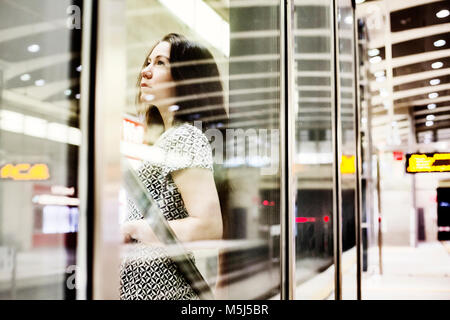 Portrait de jeune femme en attente derrière la paroi en verre sur la plate-forme de la station de métro Banque D'Images