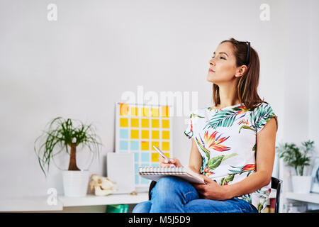 Young woman sitting on chair taking notes Banque D'Images
