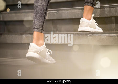 Close up of female jambes avec blanc sneakers sport courir vers le haut de l'escalier Banque D'Images