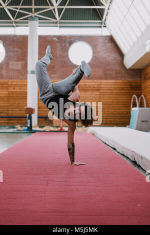 Jeune homme faisant l'exercice acrobatique in gym Banque D'Images