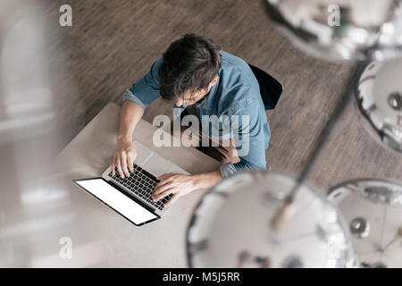 Young man working on laptop, vue du dessus Banque D'Images