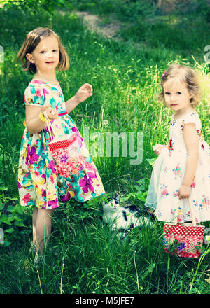 Magnifiques petites filles (soeurs) dans le parc avec le chat. L'image est teintée. Banque D'Images