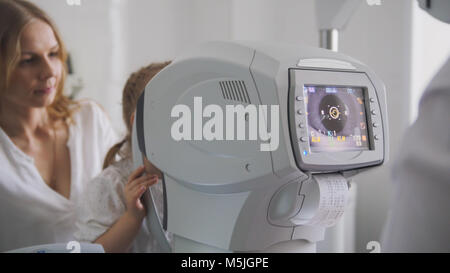 Mère et fille dans la chambre de l'ophtalmologiste optométriste - clinique en vue de l'enfant peu de contrôle Banque D'Images