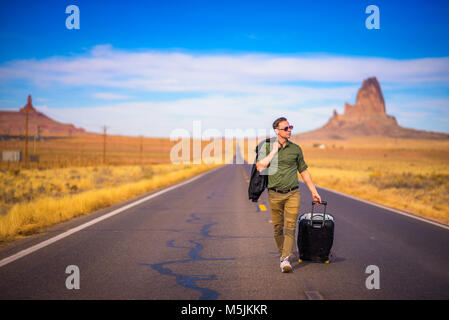 Jeune voyageur avec une valise de marcher sur une route en Arizona Banque D'Images