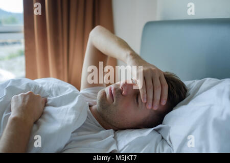 Homme étendu dans le lit à la maison souffrent de maux de tête ou gueule de bois Banque D'Images