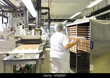 Production de pralines dans une usine pour l'industrie alimentaire - travailleur de la courroie du convoyeur avec du chocolat Banque D'Images