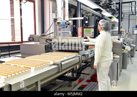 Production de pralines dans une usine pour l'industrie alimentaire - travailleur de la courroie du convoyeur avec du chocolat Banque D'Images