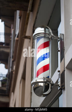 Gros plan du salon de coiffure boutique pole sign avec rayures bleu et rouge déménagement sur une façade de l'immeuble Banque D'Images