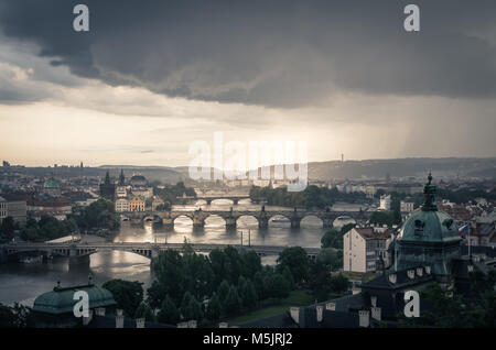 Le soleil se couche sur la rivière Vltava comme un orage l'arrosage de la ville de Prague, avec soirée dramatique et sur le célèbre pont Charles. Banque D'Images