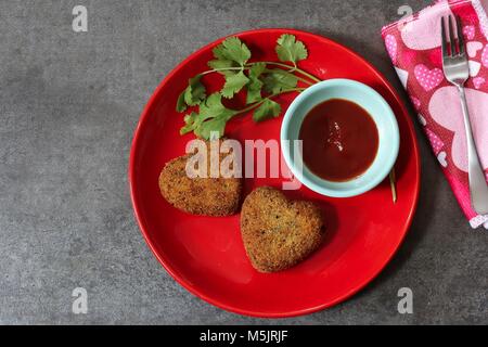 En forme de coeur les escalopes dans l'assiette rouge avec de la sauce et de coriandre / Valentines Day, De haut en bas vue de l'alimentation Banque D'Images