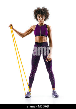 Strong girl en utilisant une bande de résistance dans sa routine d'exercice. Jeune fille africaine effectue des exercices de remise en forme sur fond blanc. Force et motivatio Banque D'Images