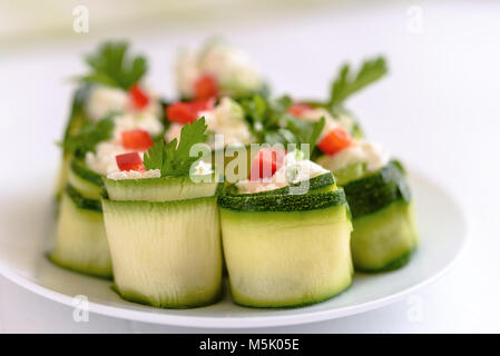 Rouleaux de courgettes farcies au fromage et ciboulette et paprika rouge. Banque D'Images