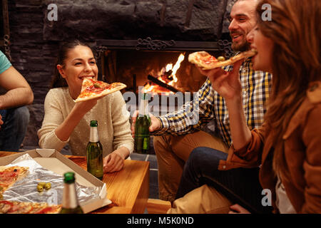 Smiling friends having party à la maison tandis que le grillage de la bière et manger des pizzas Banque D'Images