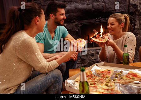 Smiling friends having fun de temps ensemble à la maison et manger des pizzas Banque D'Images