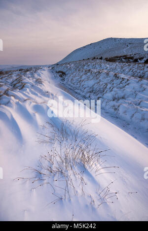 Matin d'hiver enneigé dans les collines du Peak District. Les amoncellements de neige à côté de l'allée cavalière à South Head, Hayfield, Derbyshire, Angleterre. Banque D'Images