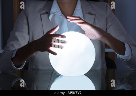 Close-up of Businesswoman Main sur Boule de cristal sur la table in Office Banque D'Images