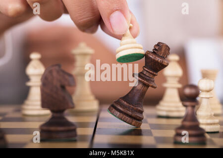 Close-up of Hand jouant aux échecs et de tomber sur King Chess Board Banque D'Images