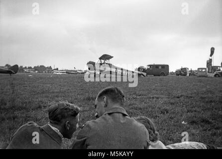 Une photographie de 1930 montrant un Focke-Wulf FW44, D-ETIS, emblème d'une croix gammée sur la queue, à un terrain d'inconnu. Beaucoup d'autres avions peuvent être vus dans l'arrière-plan. Deux hommes en uniforme militaire, et une femme, sont au premier plan. Banque D'Images