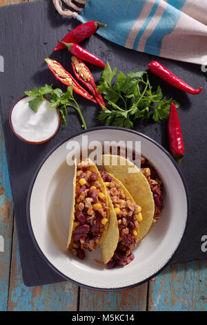 Trois tacos avec chili con carne dans un bol à côté du piment et persil frais Banque D'Images