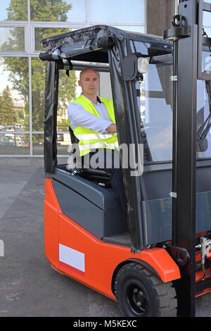 Conducteur de chariot élévateur à tête en cabine avec couverture de pluie Banque D'Images