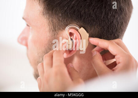 Close-up d'une personne qui met de l'aide auditive sur l'oreille de l'Homme Banque D'Images