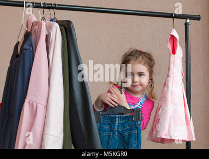 Clouse-up portrait of smiling little girl choisissant des vêtements Banque D'Images