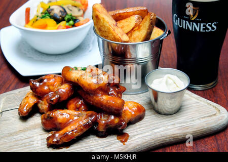 Des ailes de poulet sautées dans barbecue et sauce chili douce servi avec trempette au fromage bleu, frites et une pinte de Guinness, Doheny & Nesbitt Pub, Dublin, Irlande Banque D'Images