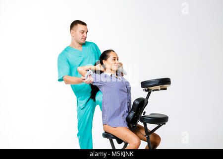 Massage thème et bureau. Jeune homme en costume bleu thérapeute faire massage dos avec son genou y dans la colonne vertébrale du travailleur féminin, femme d'affaires à l'al. Banque D'Images