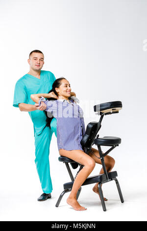 Massage thème et bureau. Jeune homme en costume bleu thérapeute faire massage dos avec son genou y dans la colonne vertébrale du travailleur féminin, femme d'affaires à l'al. Banque D'Images