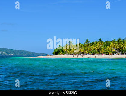 Belle plage avec des palmiers ciel bleu et l'eau turquoise, certains touristes s'amuser, se détendre et nager dans l'océan, la mer des Caraïbes Banque D'Images