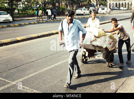 Les hommes poussant un chariot le long de la rue à Mumbai, Inde Banque D'Images