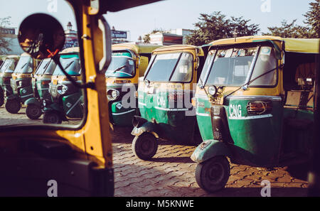 Une ligne de jaune et vert du Tuk-Tuk alignés à l'extérieur de la gare d'Agra en Inde. Banque D'Images